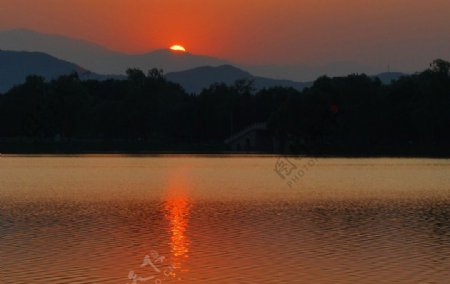 夕阳晚霞叠山树林湖面倒影波光图片