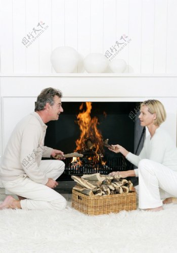 火炉边边聊天边放柴的幸福夫妻图片