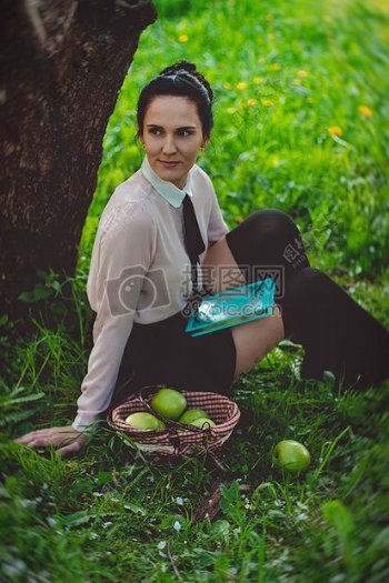 女人Weasring白色的衬衫草绿色坐在布朗下大树