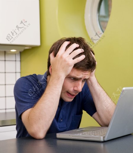 双手抱头看着电脑的男人图片