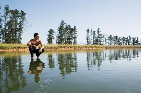 蹲在水面上看着远处的男人图片
