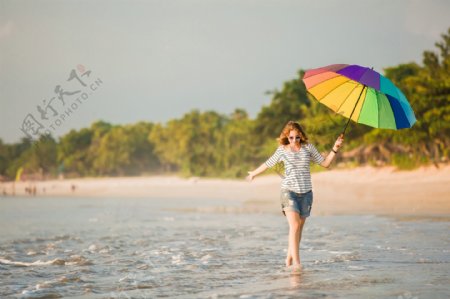 沙滩打伞散步的美女图片