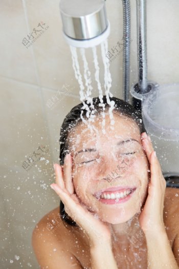 淋浴头冲洗脸部的女人图片