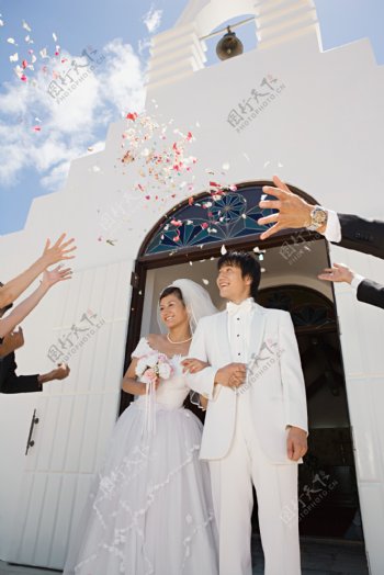 礼堂前看着飘落花瓣幸福微笑的新郎新娘图片图片