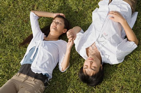 闭着眼睛躺在草地上牵着手的情侣图片图片