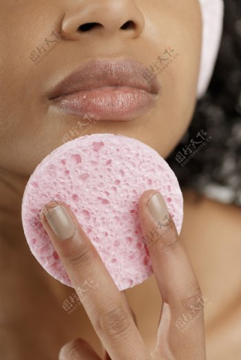 拿着粉色化妆棉放在下巴上的黑人女人图片图片