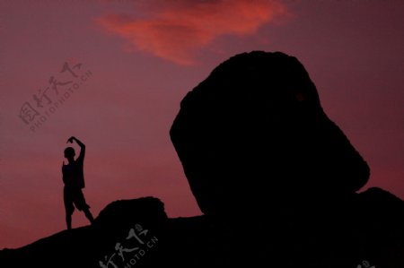 夕阳下海边岩石和人剪影图片
