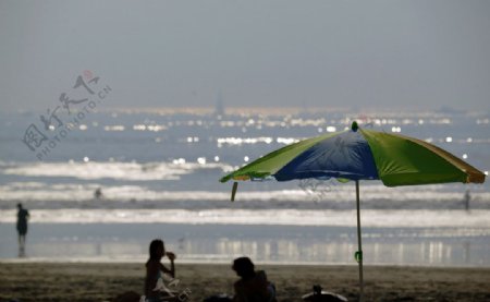 沙滩上遮阳伞下的情侣图片