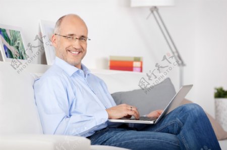 坐在沙发上操作电脑的男人图片