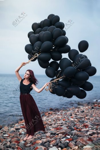 海边拿黑色气球的女人图片