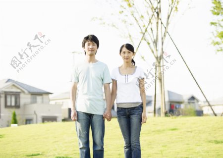 手牵手站在草坪上的青年夫妻图片