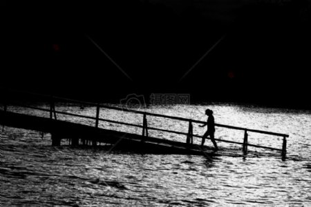 的人在黑桥在水上行走的身体剪影