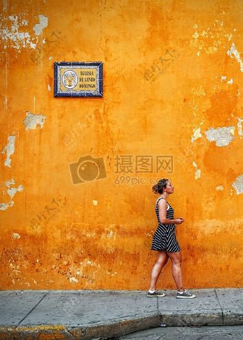 女人走旁边的橙色墙画