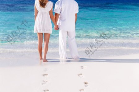 沙滩上手拉手的情侣图片