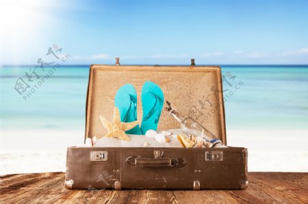 木板上行李箱里的海星和拖鞋图片