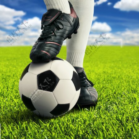 草地上脚踩在足球上的运动员图片