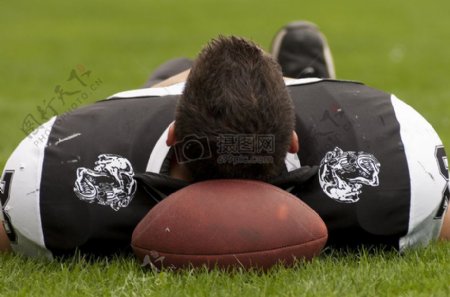 一个运动员头枕在橄榄球上