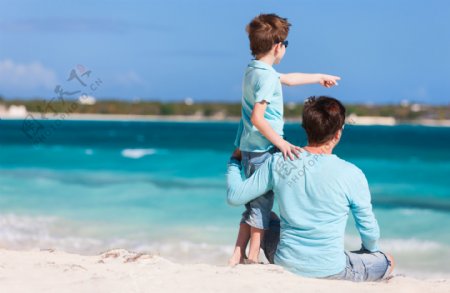 坐在沙滩上看海的外国爸爸和孩子图片