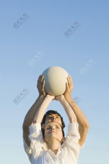 双手顶着球的男女图片