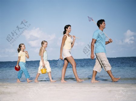 拿着鱼具走在沙滩上的一家人图片