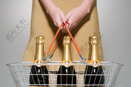 提着购物篮有三瓶香槟的女士图片