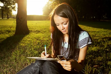 坐在草地上的写字女孩图片