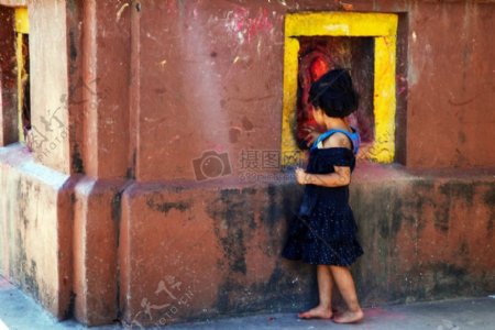 红色墙壁旁边的小女孩